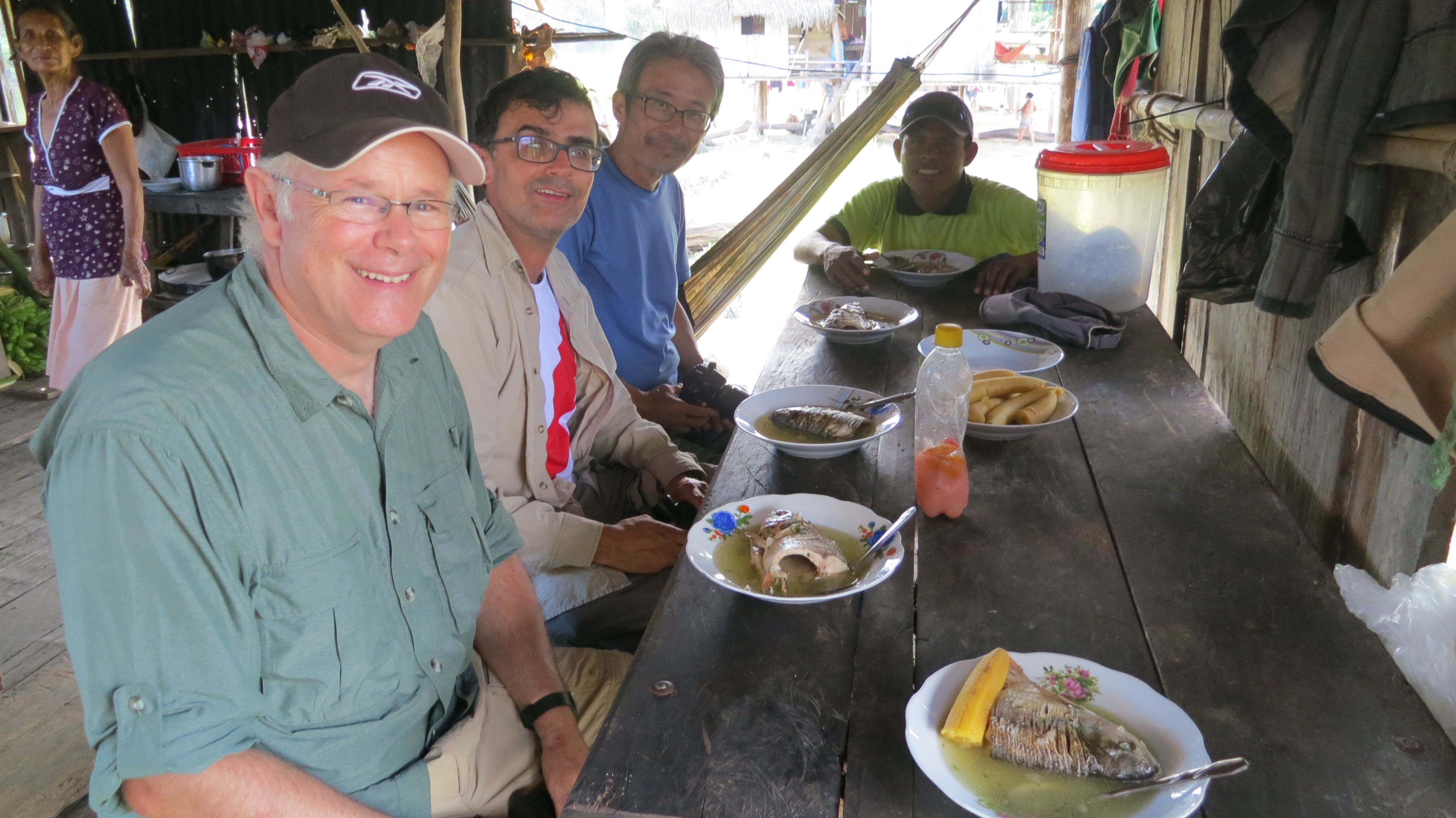 The three authors sitting on a bench having a typical Amazonian meal with freshly caught fish with plantain.